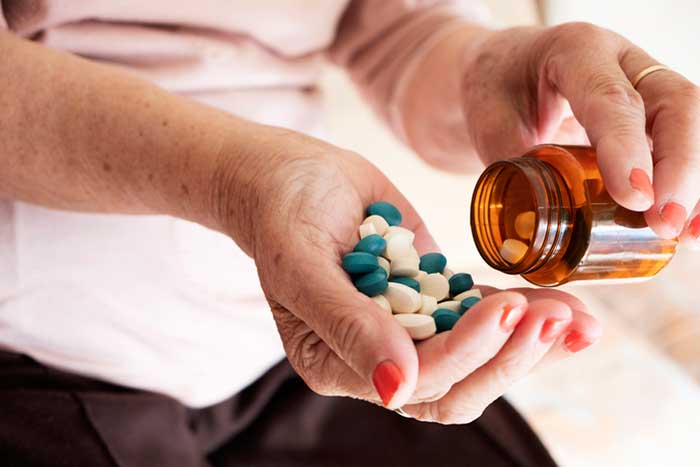 Senior woman with a pile of pills in his hand